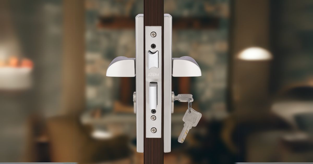 Modern door lock with two handles and keys hanging from the latch on a glass door.