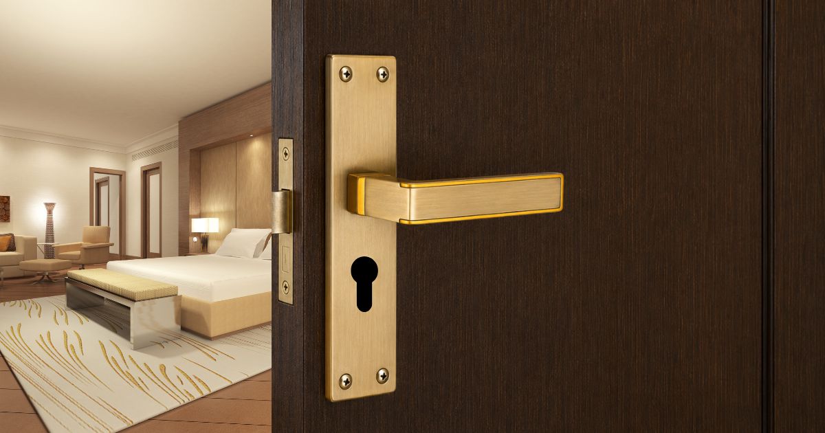 Open door reveals a luxurious hotel room with a king bed, seating area, and warm beige decor.