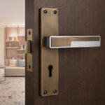 Close-up of brass door handle and keyhole on a dark wooden door, opening to a modern living room.