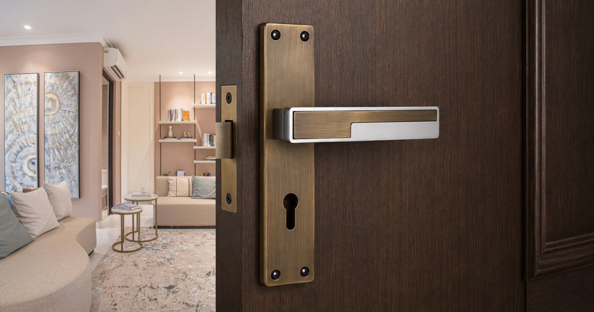 Close-up of brass door handle and keyhole on a dark wooden door, opening to a modern living room.